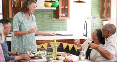 Ayakta duran ve masada oturan arkadaşlarıyla kadeh kaldıran mutlu son sınıf çifti. Kutlama, akşam yemeği, birliktelik, son sınıf yaşam tarzı ve arkadaşlık konsepti.