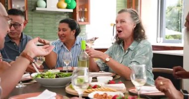 Mutlu kıdemli arkadaşlar evdeki yemek masasının etrafında konuşuyor ve şarap kadehleri kaldırıyor. Kutlama, akşam yemeği, birliktelik, son sınıf yaşam tarzı ve arkadaşlık konsepti..