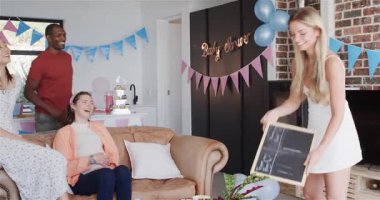 Bir grup mutlu arkadaş güneşli oturma odasındaki bebek partisinde oyun oynuyorlar. Kutlama, annelik, parti, yaz ve arkadaşlık kavramı.