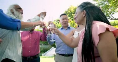 Mutlu kıdemli gelin ve damatlar bahçede arkadaşlarıyla şampanya içerken. Düğün, kutlama, romantizm, mutluluk, son sınıf yaşam tarzı ve evlilik kavramı.