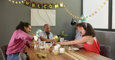 Bir grup mutlu, çok ırklı, siyah ve Çinli erkek ve kadın arkadaş masada oturmuş, oturma odasındaki yeni ev partisi için kadeh kaldırıyorlar. Kutlama, parti, yaz ve arkadaşlık konsepti.