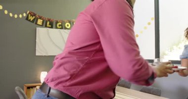 Bir grup mutlu, çok ırklı, siyah ve Çinli erkek ve kadın arkadaş oturma odasındaki bir hoş geldin partisinde masayı temizliyor. Kutlama, parti, yaz ve arkadaşlık konsepti.