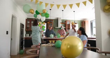 Mutlu kıdemli arkadaşlar parti için balonlarla süslüyor, konuşuyor ve alkışlıyorlar. Hazırlık, kutlama, birliktelik, kıdemli yaşam tarzı ve arkadaşlık kavramı.