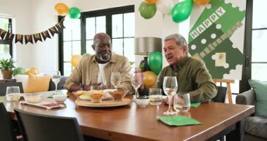 Oturma odasındaki emeklilik partisinde çok ırklı, beyaz ve siyah erkek ve kadın arkadaşlardan oluşan mutlu bir grup. Kutlama, emeklilik, parti, son sınıf yaşam tarzı ve arkadaşlık kavramı.