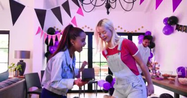 Akıllı telefon kullanan ve oturma odasındaki doğum günü partisinde selfie çeken bir grup mutlu, çok ırklı, beyaz ve Hintli erkek ve kadın arkadaş. Kutlama, doğum günü, parti, yaz ve arkadaşlık kavramı.