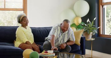 Mutlu kıdemli çeşitli adam siyah kadına hediye veriyor, balonlu selfie çekiyor. Kutlama, üst düzey yaşam, aşk, mutluluk, yaşam tarzı ve ilişki kavramı.