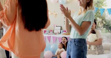 Bir grup mutlu, çok ırklı, beyaz ve siyah, bebekli kadın arkadaş güneşli oturma odasında bebek partisinde kucaklaşıyorlar. Kutlama, annelik, parti, yaz ve arkadaşlık kavramı.