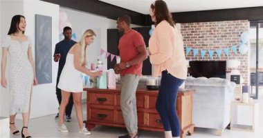 Bir grup mutlu arkadaş güneşli oturma odasındaki bebek partisinde konfeti atıyor. Kutlama, annelik, parti, yaz ve arkadaşlık kavramı.