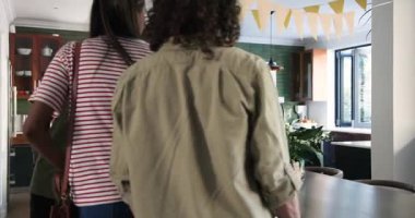 Mutfaklarına şarap ve çiçeklerle gelen mutlu çift selamlaşması. Kutlama, parti, birliktelik, yaşam tarzı ve arkadaşlık kavramı.