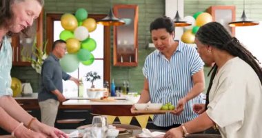 Mutlu kıdemli arkadaşlar evde akşam yemeği partisi için yemek ve şarapla konuşuyor ve sofrayı kuruyor. Hazırlık, kutlama, birliktelik, kıdemli yaşam tarzı ve arkadaşlık kavramı.