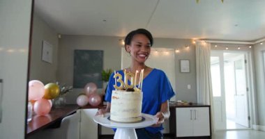 Üç mutlu çok ırklı ve beyaz bayan arkadaş güneşli oturma odasındaki bir doğum günü partisinde pastaya mum üflüyorlar. Kutlama, doğum günü, parti, yaz ve arkadaşlık kavramı.