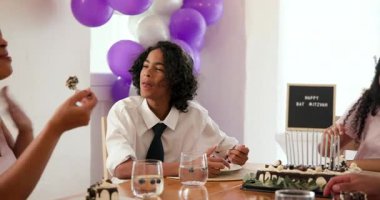 Çeşitli aileler geleneksel törenleri kutluyor, evde konuşuyor ve pasta yiyorlar. Bar mitzvah, bat mitzvah, Aile, ebeveynlik, gelenek ve kutlama konsepti.