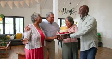 Bir grup mutlu üst düzey çok ırklı, beyaz ve siyah arkadaş oturma odasındaki bir doğum günü partisinde mum üflüyorlar. Kutlama, doğum günü, parti, son sınıf yaşam tarzı ve arkadaşlık konsepti.