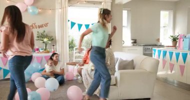 Bir grup mutlu, çok ırklı, beyaz ve siyah, bebekli kadın arkadaş güneşli bir oturma odasında bebek partisinde oyun oynuyor. Kutlama, annelik, parti, yaz ve arkadaşlık kavramı.