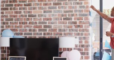 Güneşli oturma odasındaki bebek partisinde dekorasyon yapan bir grup mutlu arkadaş. Kutlama, annelik, parti, yaz ve arkadaşlık kavramı.