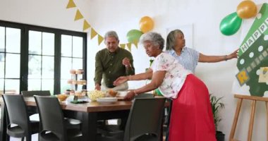 Oturma odasındaki emeklilik partisinde çok ırklı, beyaz ve siyah erkekler ve kadınlar için hazırlanan mutlu bir grup. Kutlama, emeklilik, parti, son sınıf yaşam tarzı ve arkadaşlık kavramı.