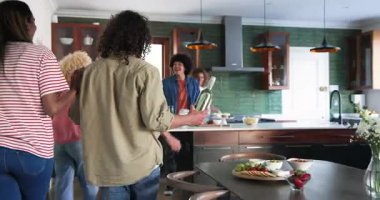 Mutfaklarına şarap ve çiçeklerle gelen mutlu çift selamlaşması. Kutlama, parti, birliktelik, yaşam tarzı ve arkadaşlık kavramı.