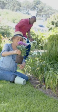 Bahçede çalışan mutlu yaşlı çiftin dikey videosu, yavaş çekim. Ev hayatı, emeklilik, doğa ve yaşam tarzı, değişmemiş..