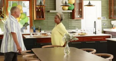 Mutlu kıdemli çift temizliği ve mutfakta balonlarla süslenmiş sandalyeleri düzenliyor. son sınıf, ev hayatı, aşk, mutluluk, yaşam tarzı ve ilişki konsepti.