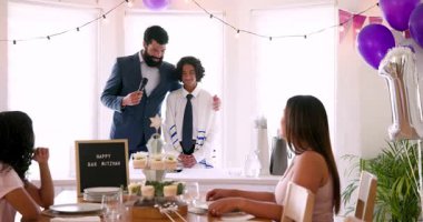 Çeşitli aileler geleneksel tören hazırlıyor ve evde dekorasyonlar ve masada yemekle konuşuyorlar. Bar mitzvah, bat mitzvah, Aile, ebeveynlik, gelenek ve kutlama konsepti.