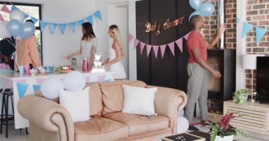 Bir grup mutlu arkadaş güneşli oturma odasında bir bebek partisi için masayı hazırlıyorlar. Kutlama, annelik, parti, yaz ve arkadaşlık kavramı.