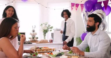 Çeşitli aileler geleneksel törenleri kutluyor, masada oturuyor, yemek yiyor ve evde sarılıyorlar. Bar mitzvah, bat mitzvah, Aile, ebeveynlik, gelenek ve kutlama konsepti.