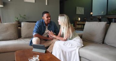 Mutlu siyah adam ve beyaz bayan partneri gülümsüyor ve nişan yüzüklerini evdeki tablet görüntülü sohbette gösteriyorlar. İletişim, ilişki, aşk, mutluluk, yaşam tarzı ve ilişki kavramı.