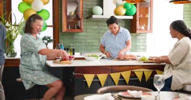 Mutlu kıdemli arkadaşlar evde akşam yemeği partisi için yemek ve şarapla konuşuyor ve sofrayı kuruyor. Hazırlık, kutlama, birliktelik, kıdemli yaşam tarzı ve arkadaşlık kavramı.