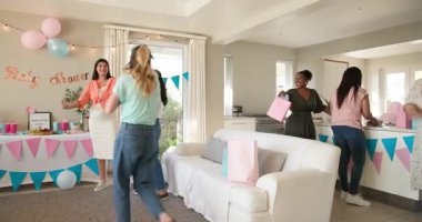 Bebekleri olan, çok ırklı, beyaz ve siyah bir grup arkadaş güneşli oturma odasındaki bir bebek partisinde temizlik ve sohbet yapıyorlar. Kutlama, annelik, parti, yaz ve arkadaşlık kavramı.