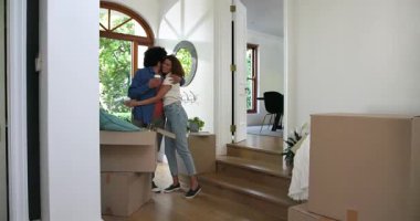 Kahveli heyecanlı bir çift, kutuların arasında yürüyor, sarılıyor ve yeni bir eve bakıyor. eve taşınma, ilişki, yaşam tarzı ve mülkiyet kavramı.