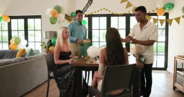 Bir grup mutlu, çok ırklı, beyaz ve Hintli erkek ve kadın arkadaş güneşli oturma odasında bir doğum günü partisi için dekorasyon hazırlıyorlar. Kutlama, doğum günü, parti, yaz ve arkadaşlık kavramı.