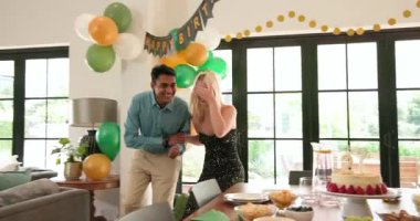 Bir grup mutlu, çok ırklı, beyaz ve Hintli erkek ve kadın arkadaş güneşli oturma odasında sarılıp kutluyorlar. Kutlama, doğum günü, parti, yaz ve arkadaşlık kavramı.