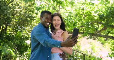 Mutlu çok ırklı ve Afro-Amerikalı çift, güneşli bir günde nişanlanıp bahçede kucaklaşıyorlar. Kutlama, nişan, parti, yaz konsepti.