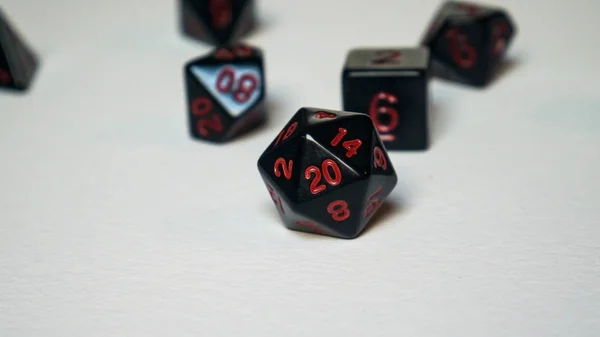 A twenty-sided dice thrown onto a white surface.
