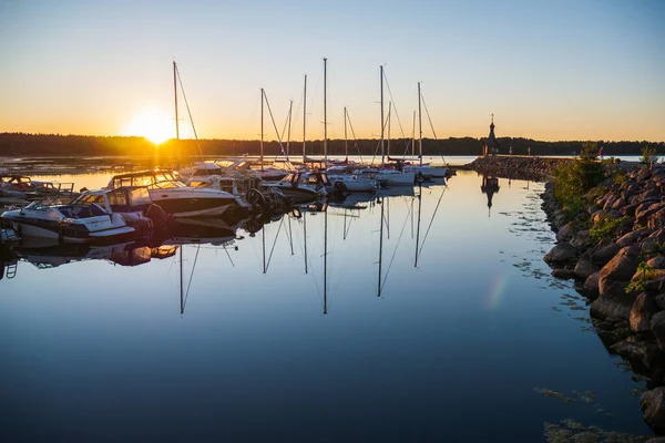 Yacht club, with a lot of different yachts and boats, ships. Beautiful nature, green forest in the background. A beautiful red yacht in the foreground.