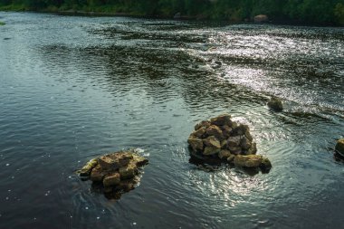 Nehrin ortasında bir taş ya da bir göl. Akan suda bir sürü kaya var. Nehir, dalgalar, akıntı..