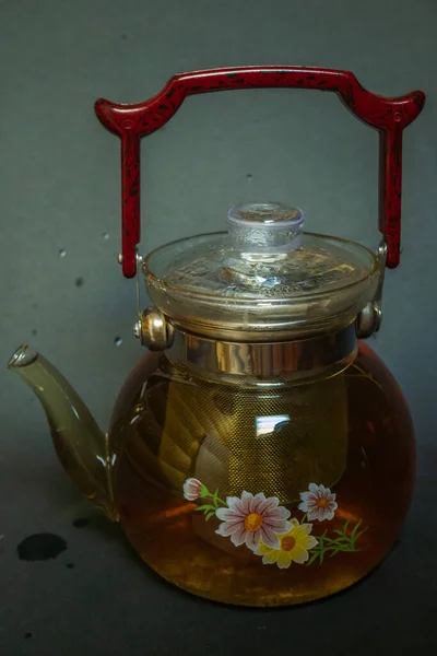 A kettle with a red handle, next to pressed green tea with mint. Tea party.