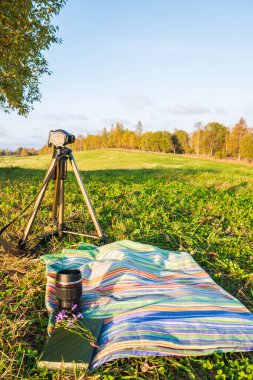 Doğada dinlenme, termos, kitap, yeşil doğanın arka planına karşı. Çimlerin üzerinde dinlen..