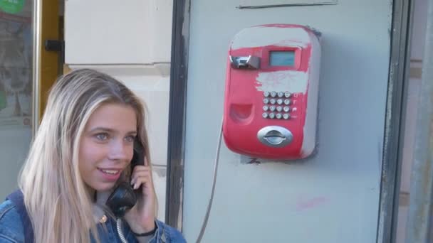 那个女孩在用公用电话说话 在街上用红色电话交谈 — 图库视频影像
