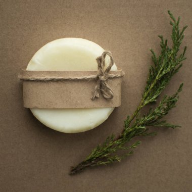 MOCKUP 0 Kraft etiketli beyaz kuru şampuan ve kraft arka planında ardıç dalı ile birlikte sicim yayı