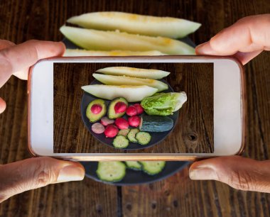 İki el bir cep telefonu fotoğraf sebze ve meyve alarak tutarak. Bir natürmort fotoğrafı