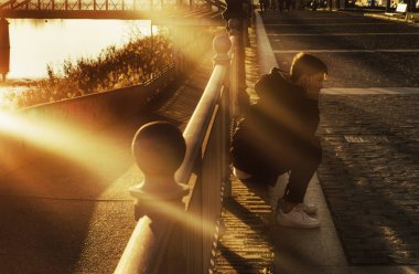 Günbatımında güneş ışınları ile şehrin günbatımı sahne şehir katta oturan çocuk