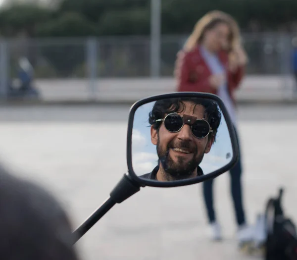 Bir motosiklet aynaya gülümseyen gözlük ve sakal ile adamın yansıması