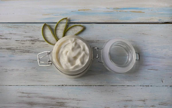 Bir cam kavanozda ev yapımı Aloe Vera krem, açık ahşap arka planda kesilmiş Aloe yaprakları ile