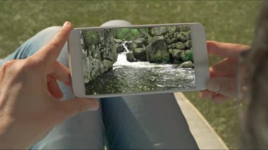 İnsan elleri su çağlayan video ile bir cep tutan. Yavaş hareket dağ nehri video