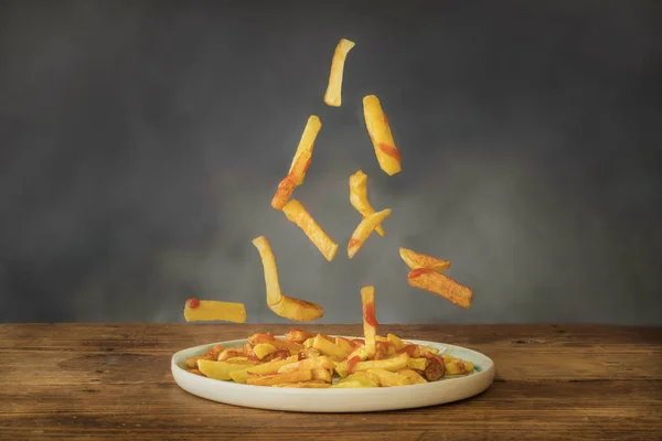 Patate fritte con ketchup che volano su un piatto di ceramica — Foto Stock