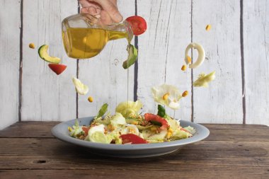 İnsan eli salataya zeytinyağı döküyor