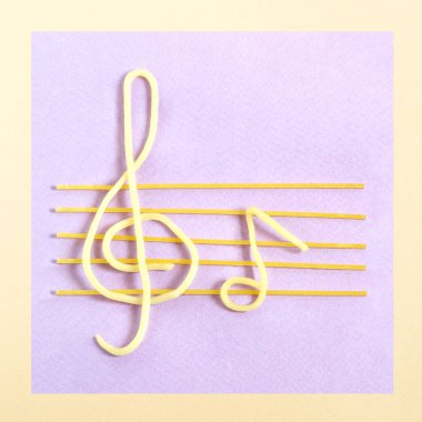 Pastel mor zemin üzerine müzikal personeli olarak spagetti. Minimalist tarzı. Yaratıcı bir fikir, hayal ve fantezi. Özgün gıda kavramı 