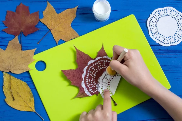 Hand-painted on dry autumn leaves by dint of paper lace napkin. Children\'s art project. DIY concept. Step by step photo instructions. Step 2. Apply drawing with paper lace napkin