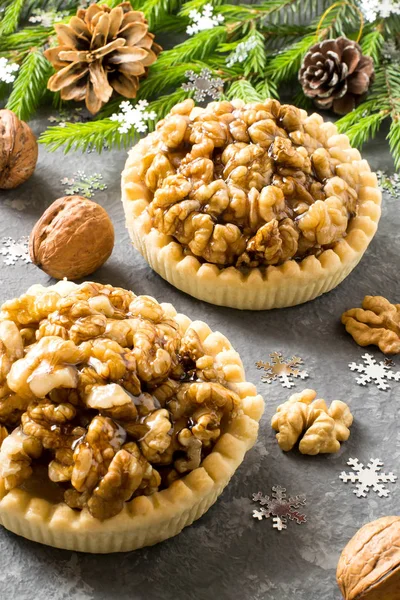 Two nut cakes with lemon jam and caramelized walnuts. Decorated Christmas tree branches. Delicious Christmas dessert. Vertical